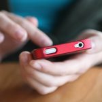 iPhone in Red leather case held in left hand, tapped on the screen
